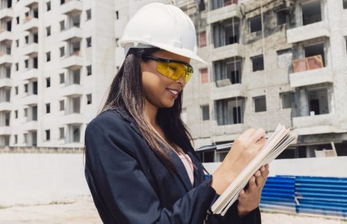 african-american-lady-safety-helmet-with-notepad-near-building-construction african-american-lady-safety-helmet-with-notepad-near-building-construction